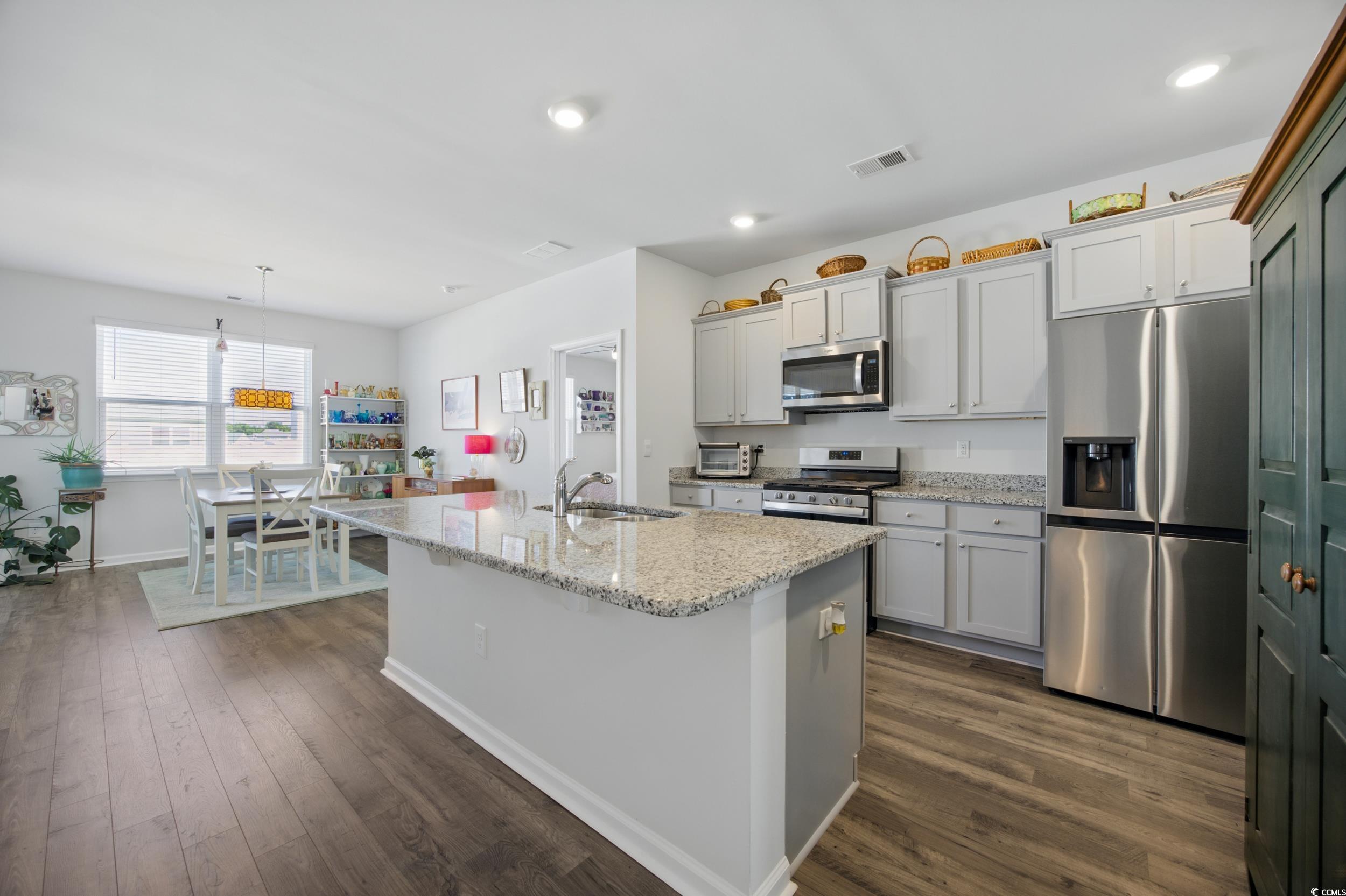 1723 Perthshire Loop Myrtle Beach, SC 29579 - Photo 12 of 34 Kitchen featuring appliances with stainless steel finishes, a sink, a kitchen island with sink, baseboards, and dark wood-style flooring