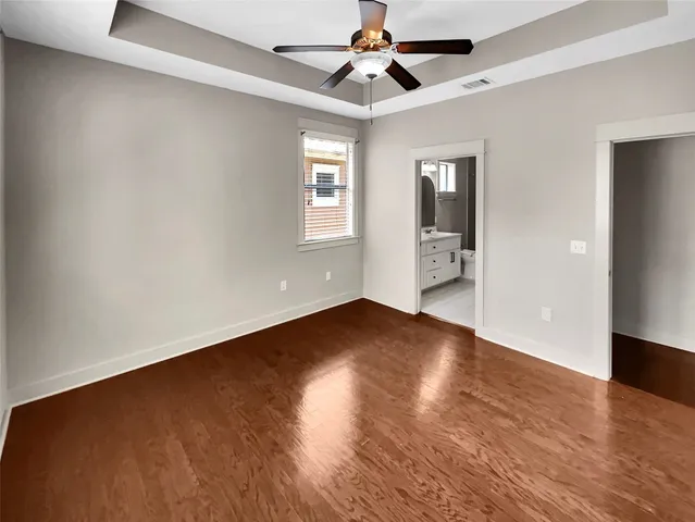 an empty room with wooden floor chandelier fan and windows