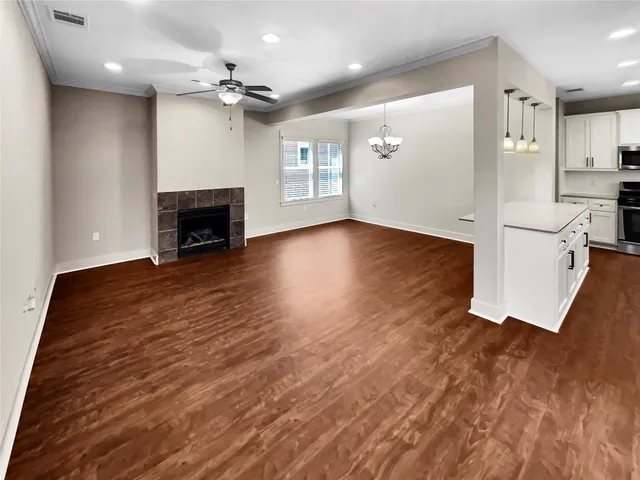 an empty room with wooden floor fireplace and windows