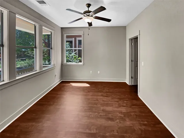 a view of an empty room with wooden floor and a window
