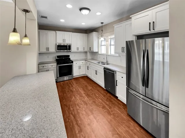 a large kitchen with stainless steel appliances granite countertop a refrigerator a stove a sink and a microwave