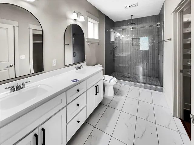 a spacious bathroom with a double vanity sink toilet and shower