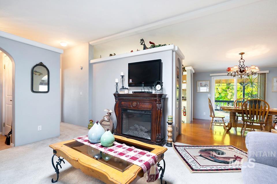 1780 Sand Hollow Road Vale, OR 97918 - Photo 18 of 41 Living area featuring arched walkways, a glass covered fireplace, a chandelier, and light wood finished floors