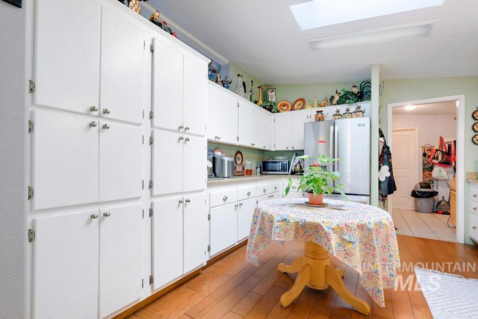 1780 Sand Hollow Road Vale, OR 97918 - Photo 20 of 41 Kitchen featuring appliances with stainless steel finishes, white cabinets, light countertops, light wood-style flooring, and a skylight