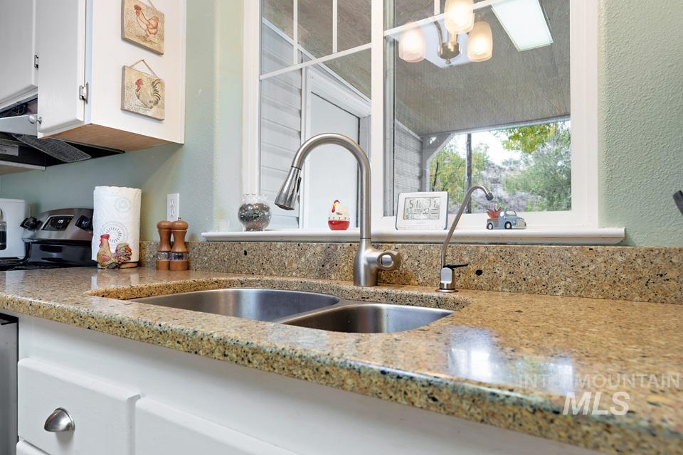 1780 Sand Hollow Road Vale, OR 97918 - Photo 22 of 41 Kitchen view of white cabinetry, electric range, a textured wall, and light stone counters
