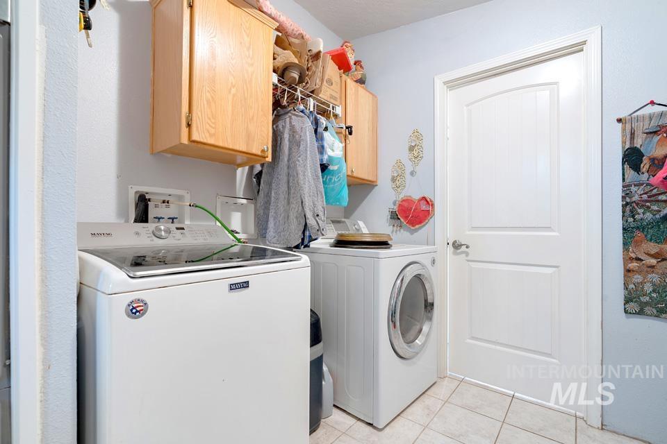 1780 Sand Hollow Road Vale, OR 97918 - Photo 36 of 41 Laundry room featuring light tile patterned floors, washing machine and clothes dryer, and cabinet space