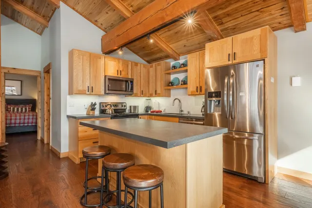 a kitchen with stainless steel appliances granite countertop a table chairs and a refrigerator