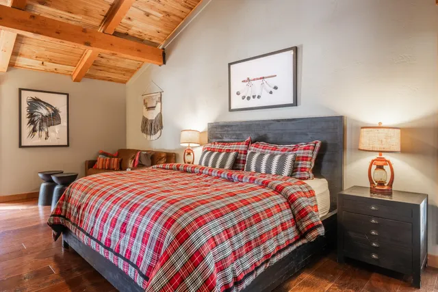 a bedroom with a bed a dresser and a large window with wooden floor