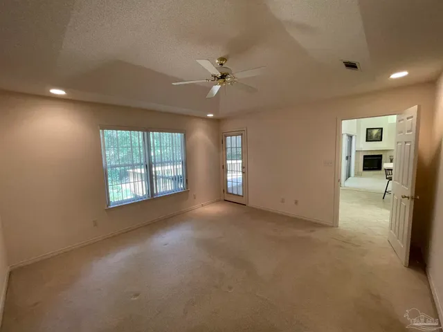 an empty room with windows and ceiling fan