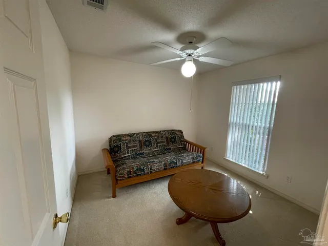 an empty room with windows and fan