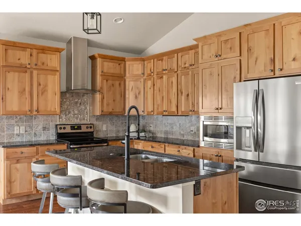 a kitchen with stainless steel appliances granite countertop a refrigerator a stove and white cabinets with wooden floor