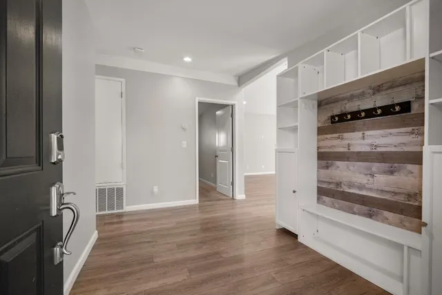 a view of an empty room with wooden floor and a window