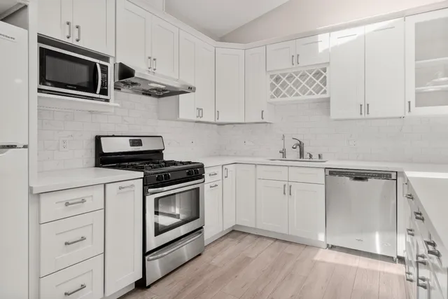 a kitchen with cabinets stainless steel appliances and wooden floor