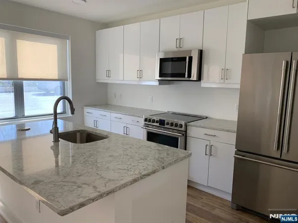 a kitchen with granite countertop a refrigerator stove and sink