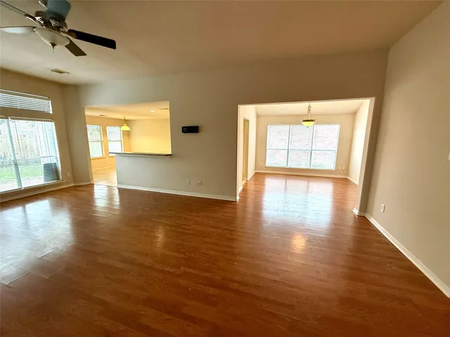 a view of an empty room with a window and wooden floor