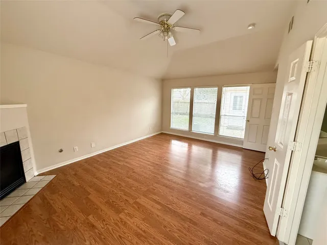 a view of an empty room with window and wooden floor