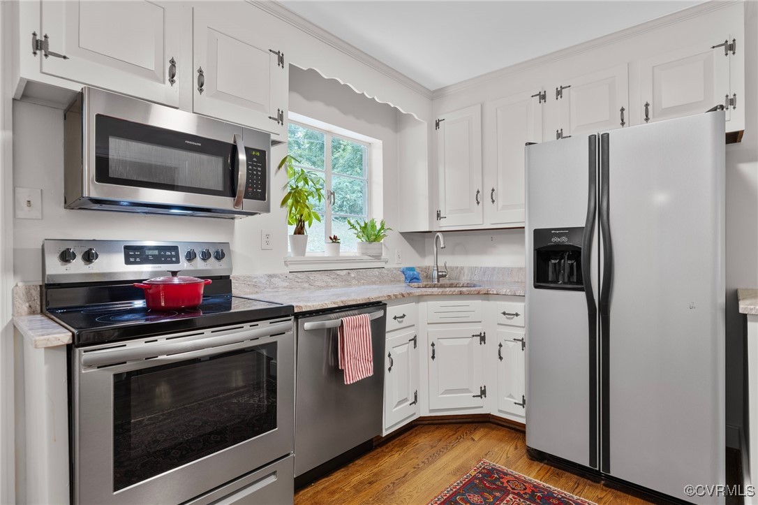 4233 Waumsetta Road Richmond, VA 23235 - Photo 6 of 32 a kitchen with stainless steel appliances a stove a microwave and white cabinets