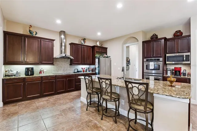 a kitchen with stainless steel appliances kitchen island granite countertop a refrigerator and a dining table