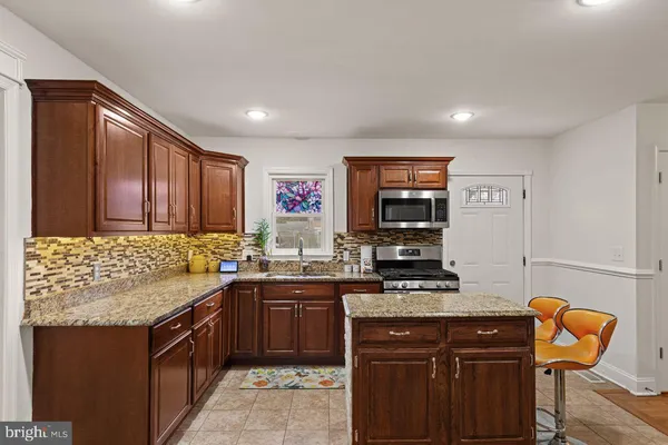 a kitchen with stainless steel appliances kitchen island granite countertop a refrigerator and stove