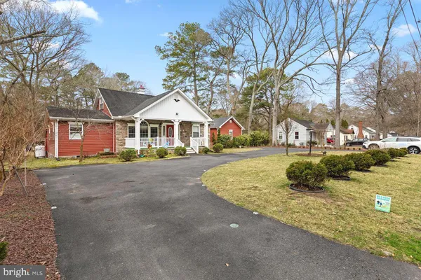 a view of large white house with a big yard and large trees