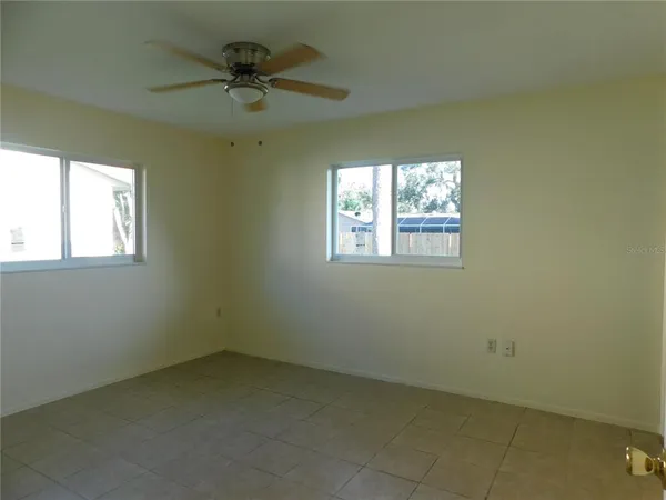 an empty room with a window and a fan