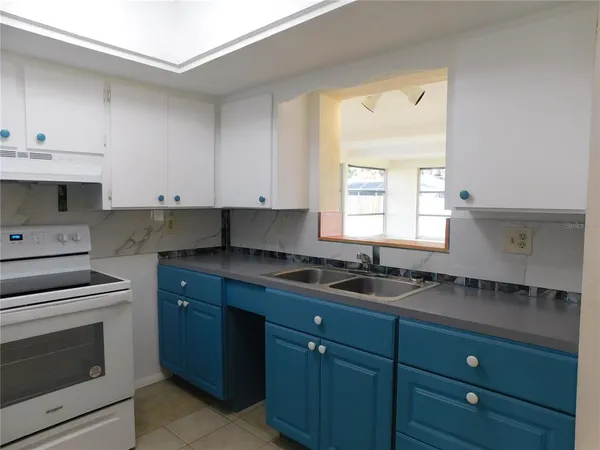 a kitchen with granite countertop a sink cabinets stainless steel appliances and a window