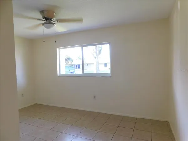 an empty room with a window and a ceiling fan