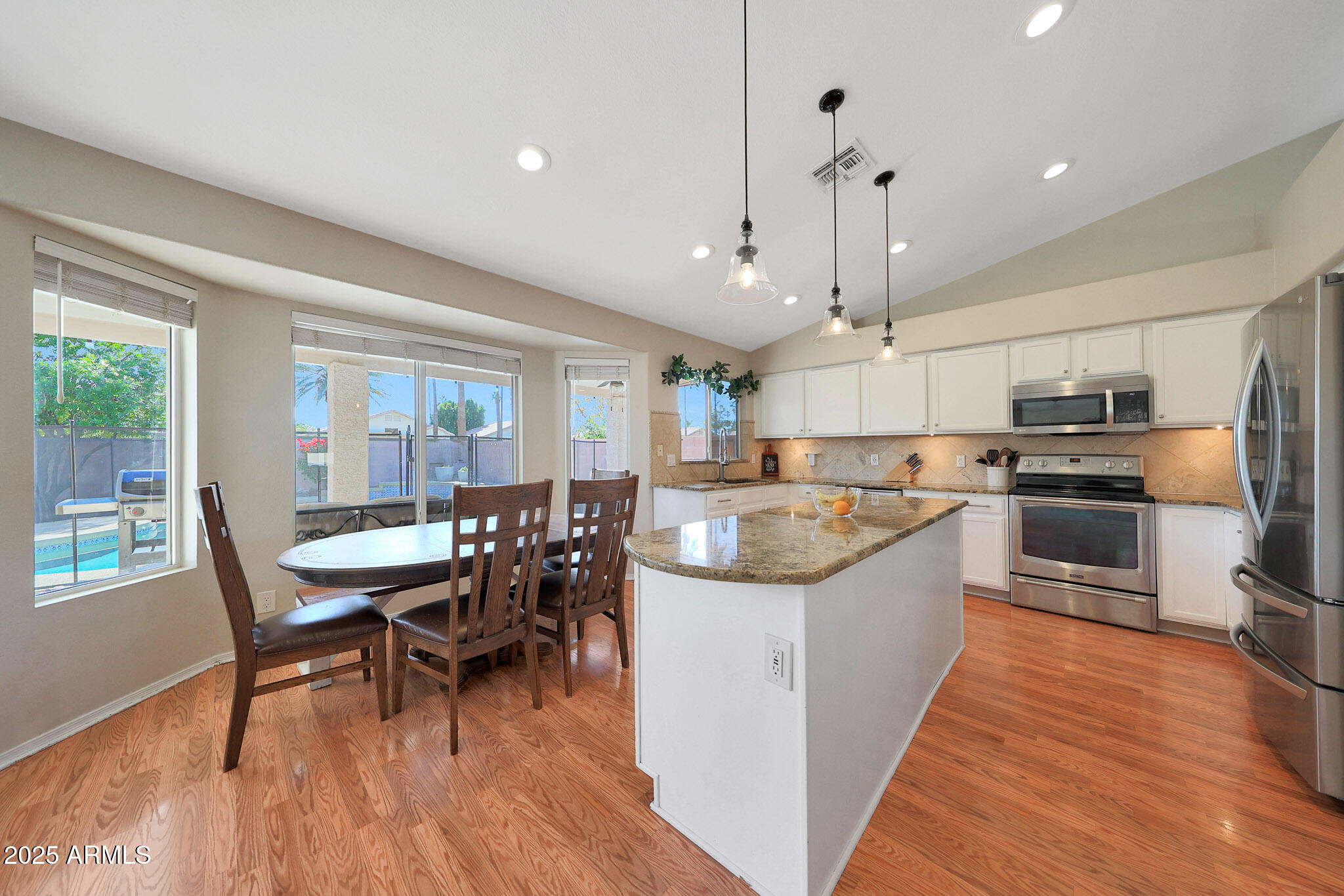 a kitchen with a dining table chairs wooden floor and appliances