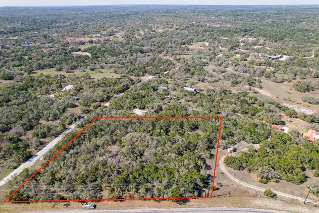 an aerial view of residential houses with outdoor space and trees