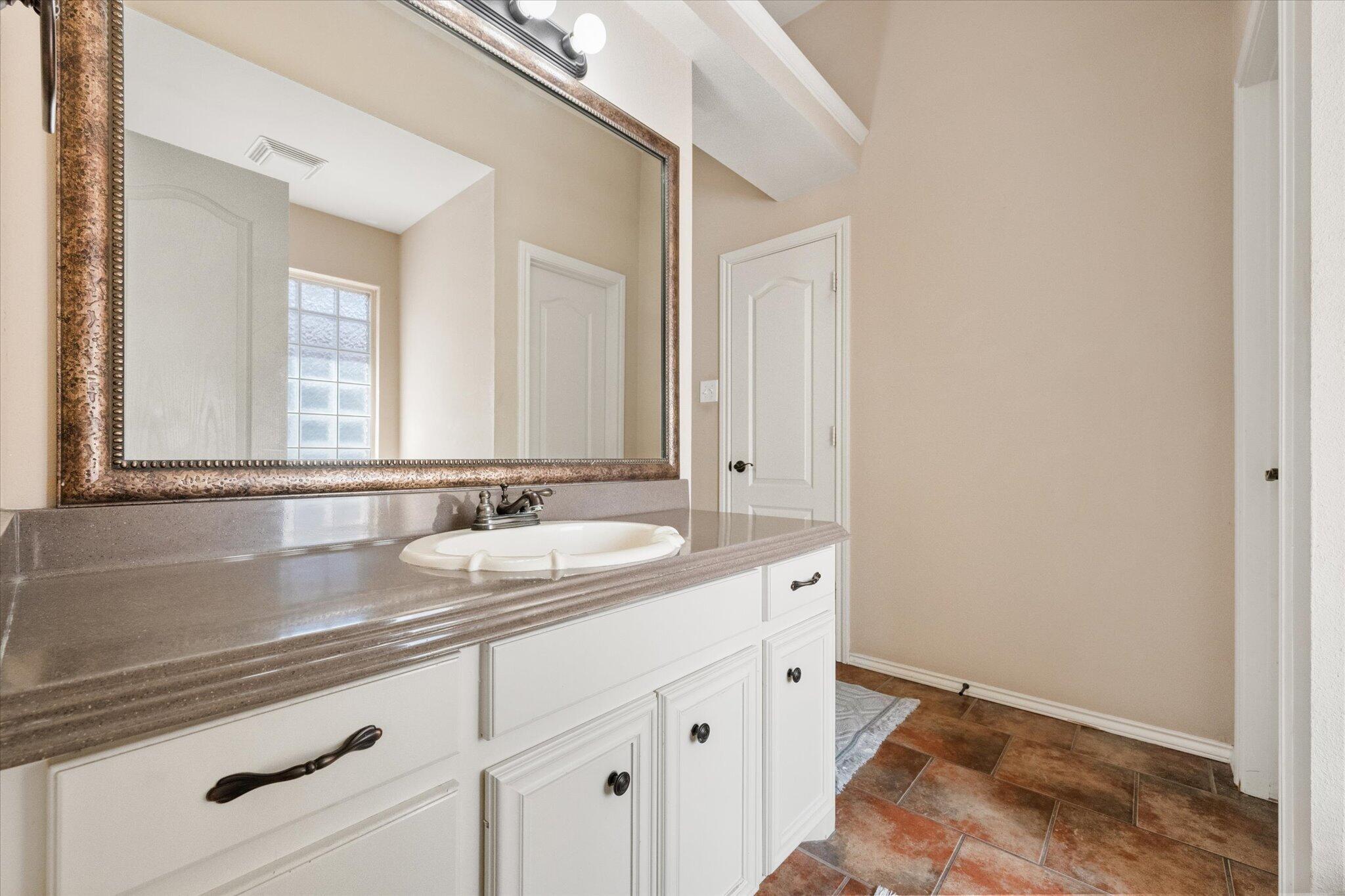 5704 107th Street Lubbock, TX 79424 - Photo 21 of 36 a bathroom with a sink and a mirror