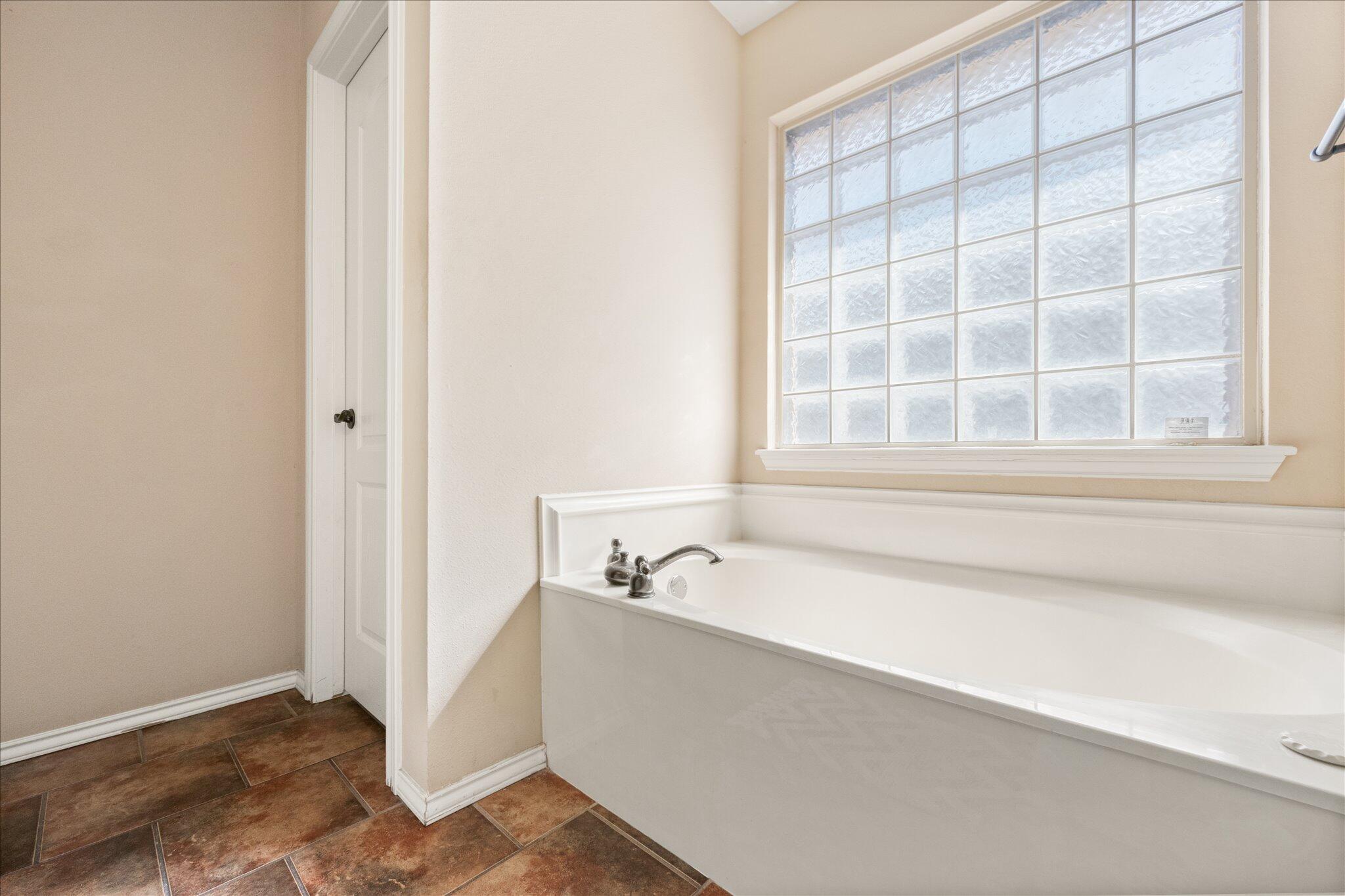 5704 107th Street Lubbock, TX 79424 - Photo 22 of 36 a bathroom with a bathtub and a window