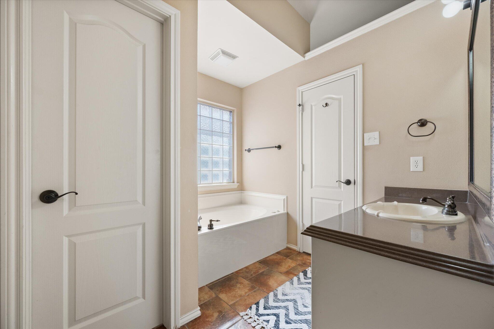 5704 107th Street Lubbock, TX 79424 - Photo 23 of 36 a bathroom with a tub sink and mirror