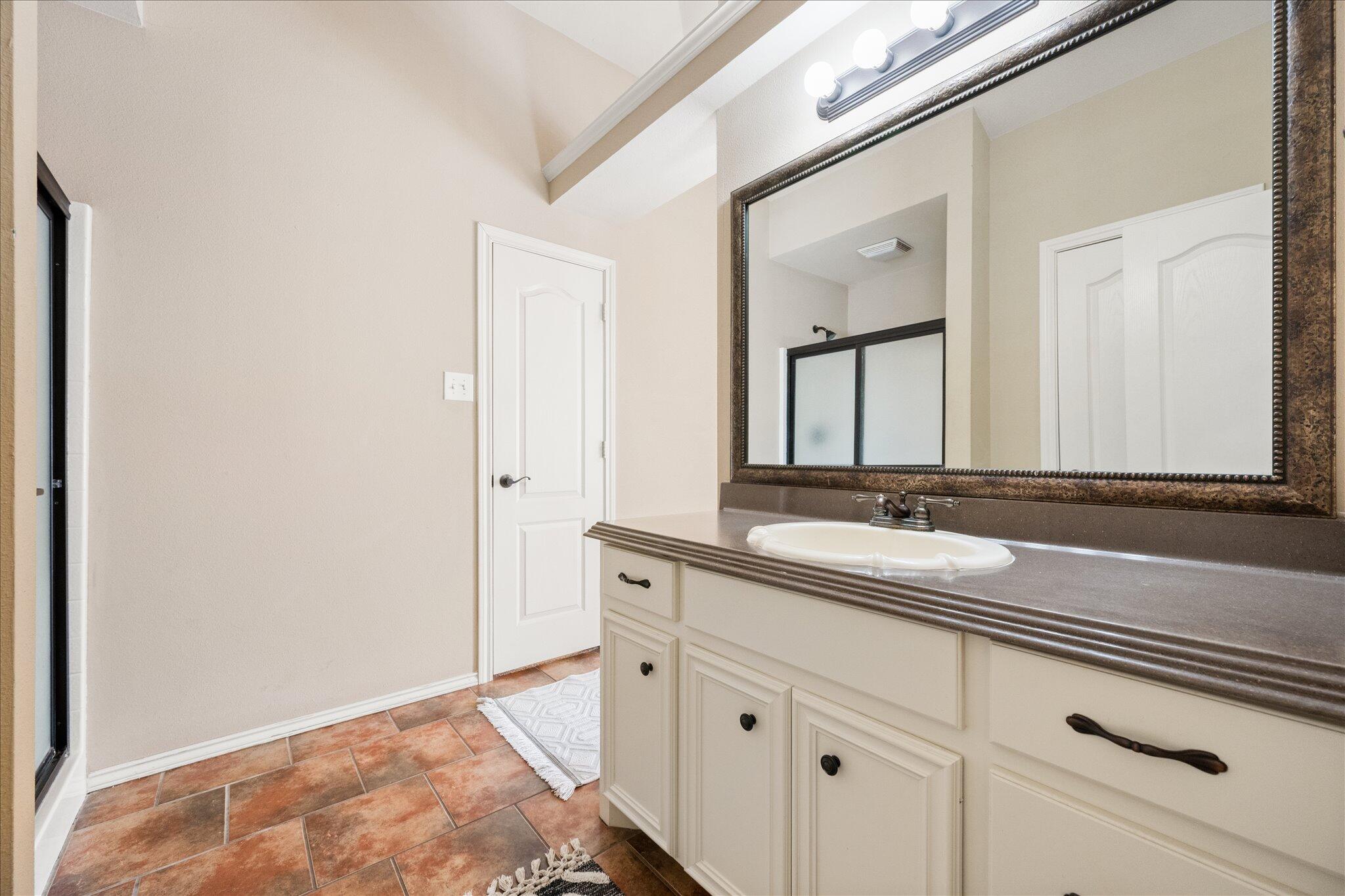 5704 107th Street Lubbock, TX 79424 - Photo 25 of 36 a bathroom with a double vanity sink and mirror
