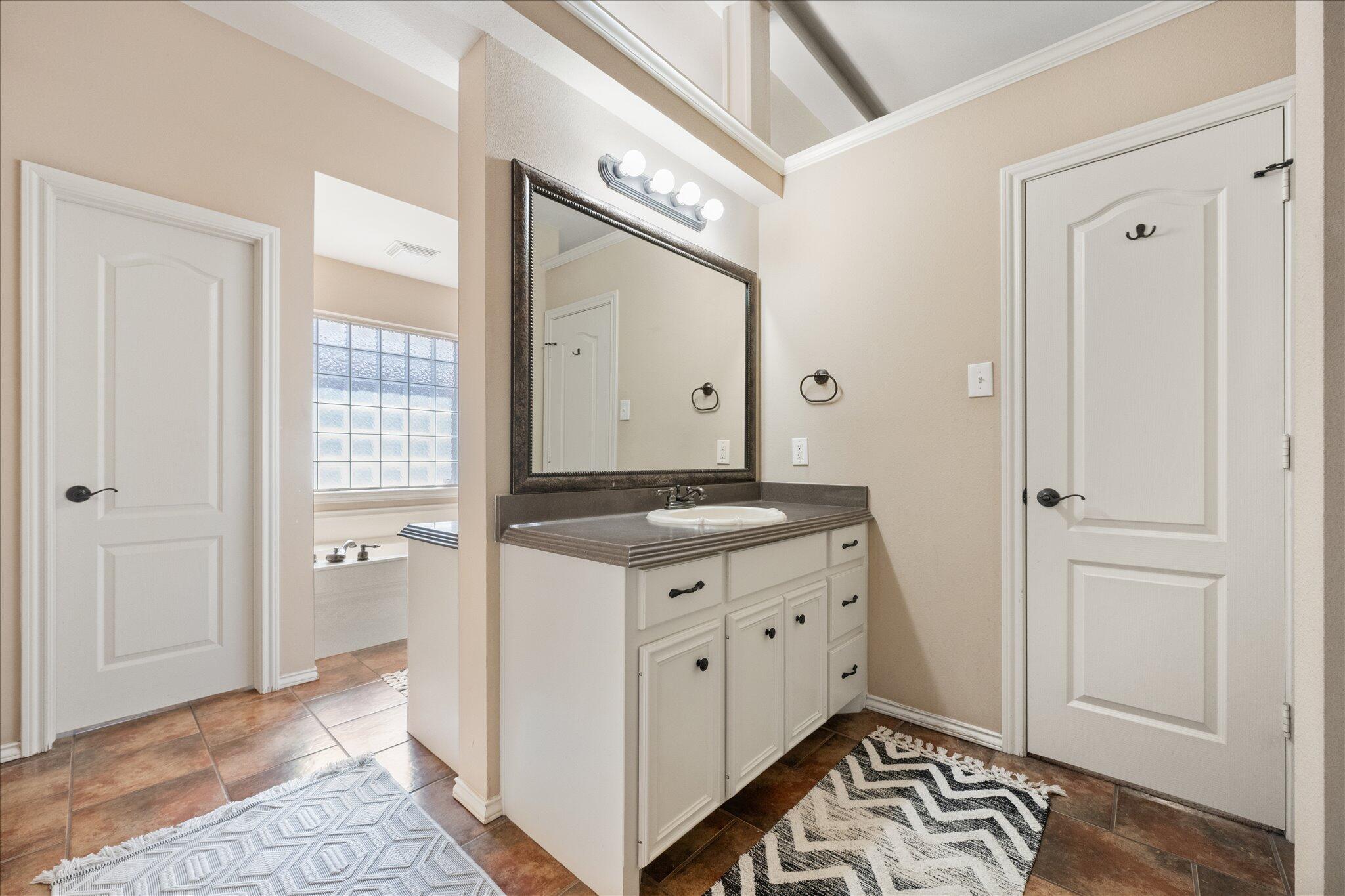 5704 107th Street Lubbock, TX 79424 - Photo 26 of 36 a spacious bathroom with a granite countertop sink and a mirror