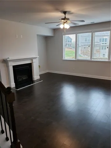 an empty room with windows fireplace and wooden floor
