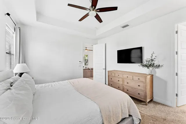 a bedroom with a bed and a flat tv screen on dresser
