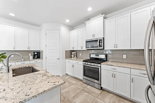 a kitchen with white cabinets sink and stainless steel appliances