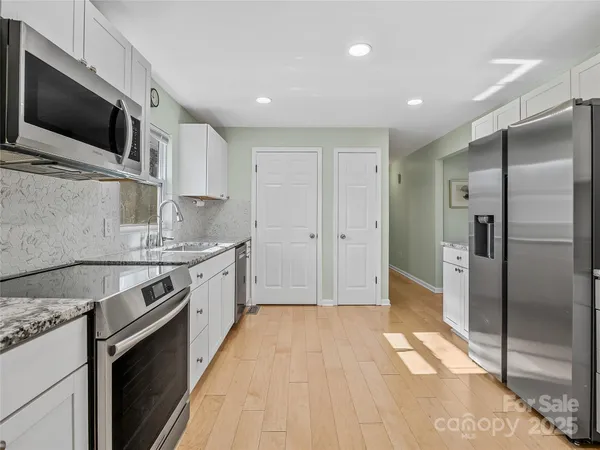 a kitchen with stainless steel appliances granite countertop a refrigerator a sink and a stove