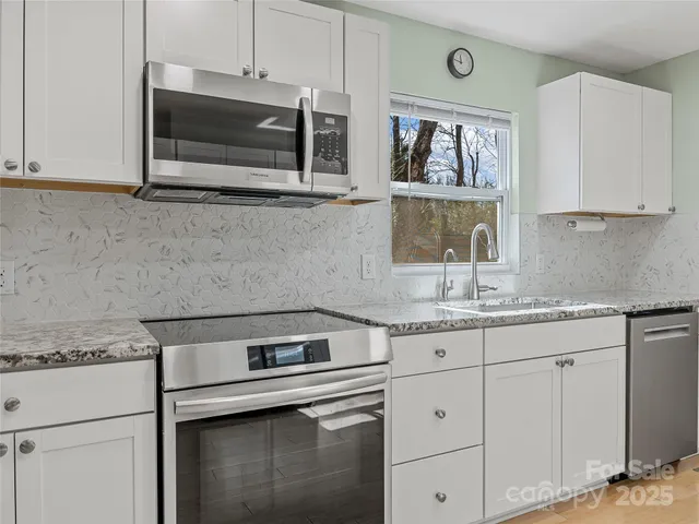 a kitchen with granite countertop white cabinets stainless steel appliances and a sink