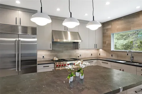 a kitchen with stainless steel appliances granite countertop a stove a sink a refrigerator and a window