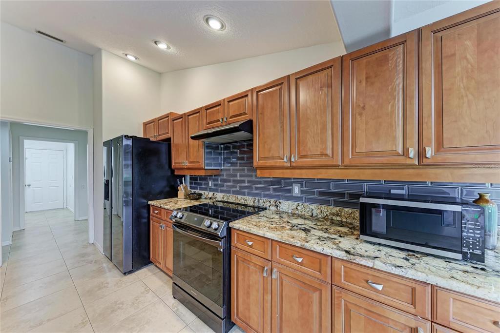 4906 Peridia Boulevard East Bradenton, FL 34203 - Photo 12 of 64 a kitchen with stainless steel appliances granite countertop a stove microwave and refrigerator