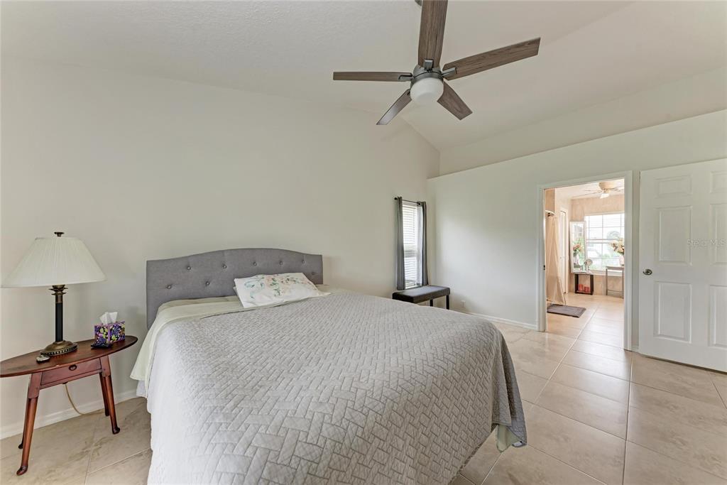 4906 Peridia Boulevard East Bradenton, FL 34203 - Photo 20 of 64 a spacious bedroom with a bed a chandelier and a window