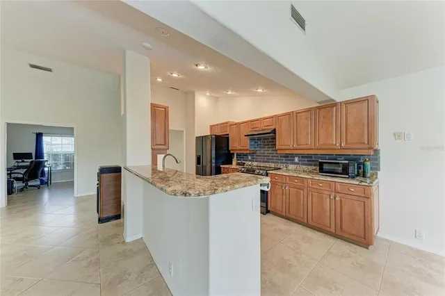 a kitchen with stainless steel appliances granite countertop a stove top oven a sink dishwasher and a refrigerator