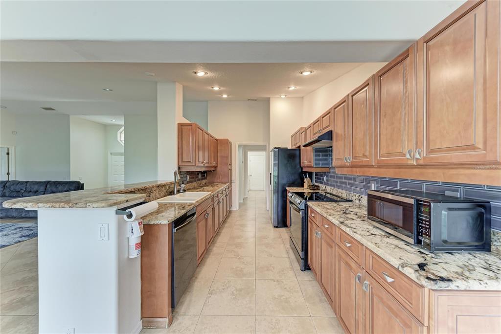 4906 Peridia Boulevard East Bradenton, FL 34203 - Photo 10 of 64 a kitchen with stainless steel appliances granite countertop a stove top oven a sink dishwasher and a refrigerator