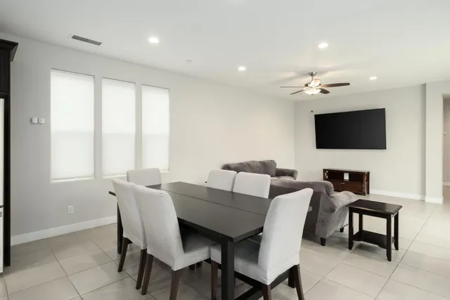 a kitchen with stainless steel appliances granite countertop a refrigerator a sink a stove a dining table and chairs