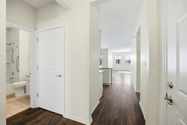 a view of a hallway with wooden floor a bathroom and a sink