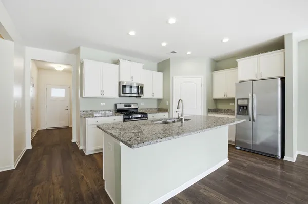 a kitchen with stainless steel appliances granite countertop a refrigerator a sink a stove a microwave and wooden floor
