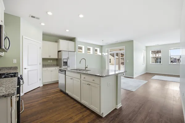 a kitchen with granite countertop white cabinets and refrigerator