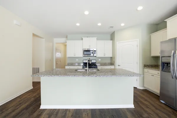 a large kitchen with granite countertop a sink a counter top space and stainless steel appliances