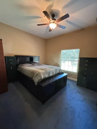 a spacious bedroom with a bed and a ceiling fan